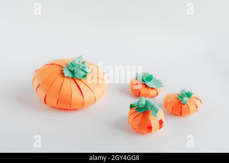 Einige orangefarbene Kürbisse aus Papier auf grauem Hintergrund. Thanksgiving Dekor und Halloween Bastelidee für Kinder Aktivitäten. Stockfoto