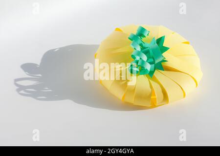 Gelber Kürbis aus Papier auf grauem Hintergrund. Thanksgiving Dekor und Halloween Bastelidee für Kinder Aktivitäten. Stockfoto