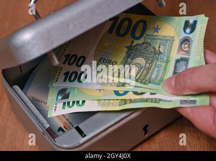 Sieversdorf, Deutschland. Oktober 2021. ABBILDUNG: Eine Frau nimmt Euro-Banknoten aus einer kleinen Kasse (posed shot). Am 07.10.2021 wird die Allianz Wealth-Studie „Allianz Global Wealth Report 2021“ vorgestellt. Quelle: Patrick Pleul/dpa-Zentralbild/dpa/Alamy Live News Stockfoto