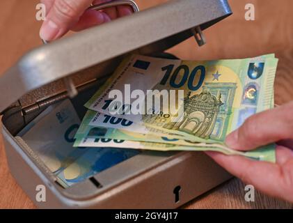 Sieversdorf, Deutschland. Oktober 2021. ABBILDUNG: Eine Frau nimmt Euro-Banknoten aus einer kleinen Kasse (posed shot). Am 07.10.2021 wird die Allianz Wealth-Studie „Allianz Global Wealth Report 2021“ vorgestellt. Bei ihren Berechnungen berücksichtigt die Allianz in der Regel Bargeld, Bankeinlagen, Wertpapiere und Ansprüche gegen Versicherungen und Pensionskassen, aber nicht Immobilien. Quelle: Patrick Pleul/dpa-Zentralbild/dpa/Alamy Live News Stockfoto