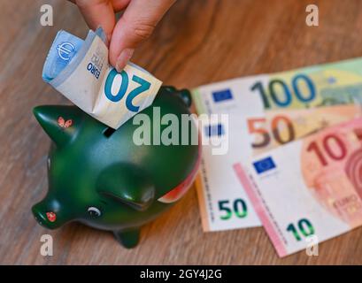 Sieversdorf, Deutschland. Oktober 2021. ABBILDUNG: Ein Mädchen legt einen 20-Euro-Schein in ein Sparschwein (posed shot). Am 07.10.2021 wird die Allianz Wealth-Studie „Allianz Global Wealth Report 2021“ vorgestellt. Bei ihren Berechnungen berücksichtigt die Allianz in der Regel Bargeld, Bankeinlagen, Wertpapiere und Ansprüche gegen Versicherungen und Pensionskassen, aber nicht Immobilien. Quelle: Patrick Pleul/dpa-Zentralbild/dpa/Alamy Live News Stockfoto