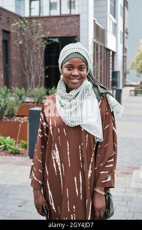 Porträt einer afrikanisch-muslimischen Frau in einem Hijab, die in der Stadt vor der Kamera lächelt Stockfoto