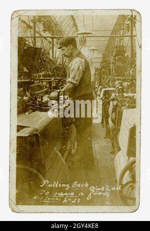 Die ursprüngliche Postkarte aus der Zeit Edwardians mit dem Titel 'Pulling Back Quick Lad to Save a Fine' zeigt die schlechten Arbeitsbedingungen dieser Zeit - niedrige Löhne, ungesunde feuchte und staubige Arbeitsplätze, Strafen und Bußgelder - . Foto eines jungen Mannes, der eine Webmaschine in einer Baumwollfabrik Betrieb, Nelson, Pendle, Lancashire, Großbritannien, um 1905.