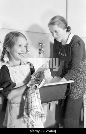 Mitglieder einer kinderreichen Familie bei der Hausarbeit, Deutsches Reich 30er Jahre. Mitglieder einer Großfamilie, die die Hausarbeit, Deutschland 1930. Stockfoto