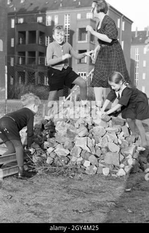 Mitglieder einer kinderreichen Familie spielen hinter dem Wohnhaus, Deutsches Reich 30er Jahre. Mitglieder einer Großfamilie spielen hinter dem Wohnblock, Deutschland 1930. Stockfoto