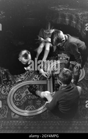 Mitglieder einer kinderreichen Familie spielen im Wohnzimmer, Deutsches Reich 30er Jahre. Mitglieder einer Familie spielen im Wohnzimmer, Deutschland 1930. Stockfoto