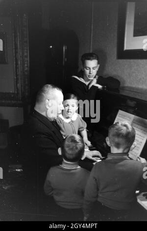 Mitglieder einer kinderreichen Familie beim Klavierspielen, Deutsches Reich 30er Jahre. Mitglieder der Großfamilie, Klavier spielen, Deutschland 1930. Stockfoto