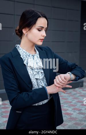 Geschäftsfrau im Anzug schaut auf die Uhr Stockfoto