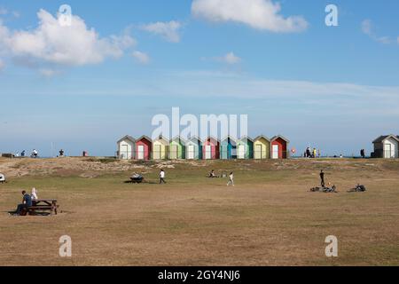 Blyth UK: 26. September 2021: Farbenfrohe Strandhütten am Meer mit Menschen, die einen Spätsommertag genießen Stockfoto