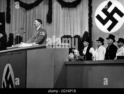 Hitler hält eine Rede im Sportpalast, um die Fertigstellung der neuen Reichskanzlei zu markieren. Hinter ihm stehen Vorarbeiter in Gildenkleid, die am Bau beteiligt waren. [Automatisierte Übersetzung] Stockfoto