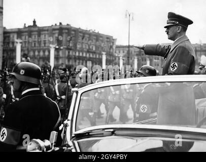 Adolf Hitler begrüßt Polizeieinheiten, die mit einem Mercedes W 150 Cabriolet am Wilhelmplatz vorbeimarschieren. Vor dem Auto stehen der Kommandant der Leibstandarte Adolf Hitler, Obergruppenführer Sepp Dietrich und Reichsleiter SS Heinrich Himmler. Dies war das erste Jahr, in dem SS-Angehörige diese herausragende Stellung innehaten, nachdem zuvor Angehörige der Wehrmacht mit Hitler in der ersten Reihe gestanden hatten. [Automatisierte Übersetzung] Stockfoto