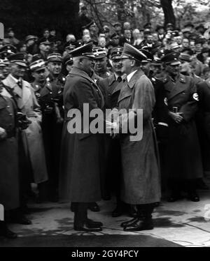 Adolf Hitler schüttelt sich die Hände mit dem Reichsschatzmeister der NSDAP, Franz Xaver Schwarz. Im Hintergrund, von links, sind Fritz Todt, Rudolf Heß, Heinrich Himmler und Franz Ritter von Epp zu sehen. [Automatisierte Übersetzung] Stockfoto