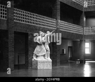 „Anlässlich des Geburtstages von Joseph Goebbels wurde am 29. Oktober 1934 im Großen Atrium des Berliner Rundfunks (heute: Haus des Rundfunks) in der Masurenallee in Berlin-Westend eine Statue des Bildhausers Hans Schellhorn enthüllt. Die Inschrift auf der Basis der Statue, auf der ein Mann Hitlers Gruß gibt, lautet programmatisch: ''Broadcasting Serves''. Zuvor stand dort die Skulptur ''die Nacht'' von Georg Kolbe. [Automatisierte Übersetzung]' Stockfoto