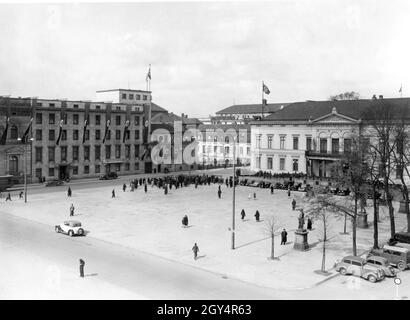 1938 hat sich eine kleine Menge auf dem Wilhelmplatz in Berlin-Mitte versammelt. Auf der linken Seite befinden sich die Kanzlereien des Neuen und Alten Reiches, auf der rechten Seite das Ordenspalais. [Automatisierte Übersetzung] Stockfoto