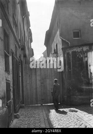 1934 steht ein Mann vor der Gasse am Krögel in Berlin-Mitte, die mit einer Dielenwand verschlossen ist. Die Abbrucharbeiten an den alten Gebäuden und Häusern waren kurz vor dem Beginn. [Automatisierte Übersetzung] Stockfoto