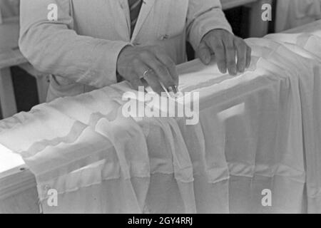 Hände des Vorarbeiters Fallschirm in einer Näherei, Deutschland 1940er Jahre. Hände von einem häuptling an einem Fallschirm nähen Fabrik, Deutschland 1940. Stockfoto