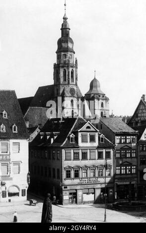 'Das Foto von 1933 zeigt den Marktplatz mit Prinz-Albert-Denkmal in Coburg und die Morizkirche im Hintergrund. Links von der Steingasse befindet sich das Haus mit der Hofapotheke, die 1543 gegründet wurde. Auf der rechten Seite der Gasse, der Besitzer ''Otto Frenkel vorm. C.A. Bischoff“ verkauft unter anderem „Teppiche, Farben, Öle, Materielle Güter, Zigarren, Tabak, Kolonialwaren'. Daneben befindet sich das Modehaus 'Ferdinand Marquardt' mit ''Mützen und Mützen' und 'Männerbekleidung und Jungenbekleidung''. [Automatisierte Übersetzung]' Stockfoto