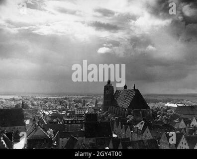 Dunkle Wolken, aus denen ein paar Sonnenstrahlen durchbrechen, ziehen 1939 am Himmel über Ingolstadt vorbei. Das Bild wurde wahrscheinlich vom Pfeifturm oder dem Kirchturm von St. Moritz aufgenommen. Der Blick geht über die Altstadt Richtung Westen zur Hohen Schule in der Hohen-Schul-Straße (links), Theresienstraße und Kreuzstraße mit dem Liebfrauenmünster (Bildmitte) und dem Ostflügel des ehemaligen Jesuitenkollegiums in der Konviktstraße (rechts). [Automatisierte Übersetzung] Stockfoto