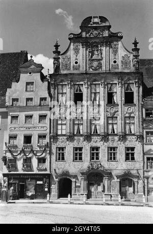 „das Historische (oder Alte) Rathaus von Landsberg am Lech steht auf dem Hauptplatz (Nr. 152) und erhielt 1719 von Dominikus Zimmermann eine reich verzierte Fassade. Im schmalen Haus Nr. 151 links davon feierte Luzian Haggenmüllers Laden 1937 sein hundertjähriges Bestehen als Eisenwarenhandlung, bot aber auch ''Auto - Benzin - Öl'' an. Vor dem Laden befindet sich eine Benzinpumpe mit der Aufschrift ''Shell''. [Automatisierte Übersetzung]' Stockfoto