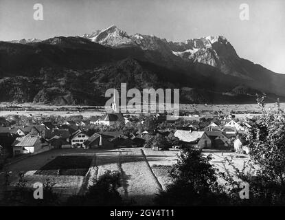 'Das Foto zeigt Garmisch-Partenkirchen (Kreis Partenkirchen) um das Jahr 1900. Im Zentrum des Dorfes befindet sich die Pfarrkirche Maria Himmelfahrt. Hinten rechts befindet sich die 'Villa Christina' (Schnitzschulstraße Nr. 19, mit Eckturm), die 1893 vom Mannheimer Zigarrenhersteller Georg Ludwig Mayer-Doss erbaut wurde. Dahinter sieht man das Wettersteingebirge mit Kreuzjoch, Alpspitze, Höllentalspitzen, Zugspitze, Waxenstein (von links nach rechts). Foto aus dem Kunstverlag von Max Stuffler aus München. [Automatisierte Übersetzung]' Stockfoto