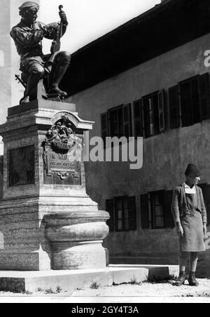 „Dieses Denkmal vor der Kirche St. Peter und Paul in Mittenwald wurde für Matthias Klotz, den Gründer des Geigenbaus im Dorf, errichtet. Der Junge rechts ist ein Nachkomme des Geigenbauers. Auf dem Sockel ist die Inschrift: ''M. Klotz / Geb. 1653 Starb 1743''. Undatierte Aufnahme des Frankfurter Fotografen Paul Edmund Hahn, vermutlich um 1920. [Automatisierte Übersetzung]' Stockfoto