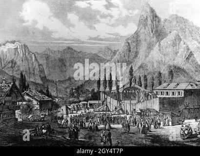 Dieser Stich von Carl Emil Doepler aus der Zeit um 1860 zeigt die Bühne für das Passionsspiel in Oberammergau. Zahlreiche Besucher sind vor dem Hotel versammelt. Im Hintergrund rechts sieht man den Kofel. [Automatisierte Übersetzung] Stockfoto