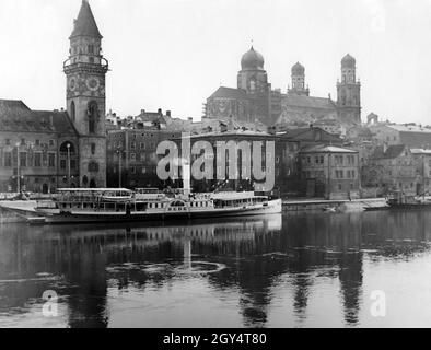 Das 1905 gebaute Dampfpassagierschiff DFS Hebe liegt an der Kaimauer der Donau vor dem Rathausplatz in Passau. Auf der linken Seite befindet sich das Alte Rathaus mit dem Rathausturm, auf der rechten Seite des Platzes befindet sich das Neue Rathaus (Gebäude mit Erker). Dahinter erhebt sich der Dom St. Stephan über den Häusern der Stadt. Das undatierte Foto hätte um 1920 aufgenommen werden können. [Automatisierte Übersetzung] Stockfoto