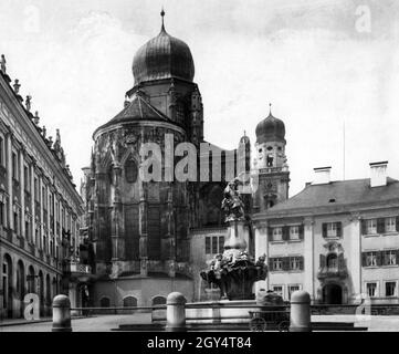 Hinter dem Wittelsbacher Brunnen, der auf dem Residenzplatz in Passau steht, sieht man den Ostchor des Stephansdoms. Auf der linken Seite grenzt der Platz an die Neue Residenz, auf der rechten Seite an das Marschallhaus (oder Palast des fürstbischöflichen Kanzlers). Das undatierte Foto wurde wahrscheinlich um 1935 aufgenommen. [Automatisierte Übersetzung] Stockfoto