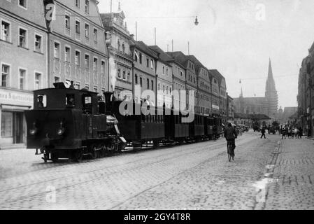 "Früher führte eine Schmalspurbahn von der Hauptstraße des Regensburger Stadtamhofs (im Bild) zur Walhalla-Gedenkstätte. Auf der linken Seite in der Einkaufsstraße befindet sich die ''Marien-Apotheke''. Im Hintergrund laufen Passanten in Richtung der Steinernen Brücke, die in die Altstadt von Regensburg mit dem Dom führt, der gerade renoviert wird. [Automatisierte Übersetzung]' Stockfoto