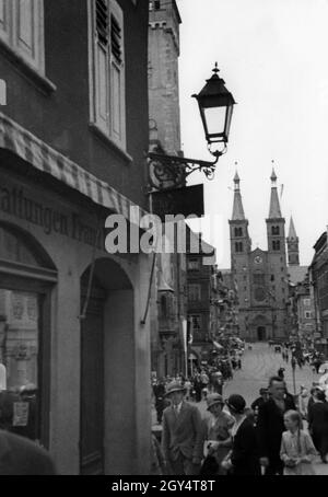 Zahlreiche Passanten säumen 1933 die Bürgersteige an der Domstraße in Würzburg. Am Ende der Straße ist das Westportal mit dem Eingang zum Würzburger Dom zu sehen. [Automatisierte Übersetzung] Stockfoto