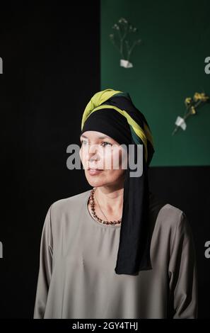 Porträt einer eleganten reifen Frau in muslimischer Kleidung, die gegen die moderne Wand schaut Stockfoto