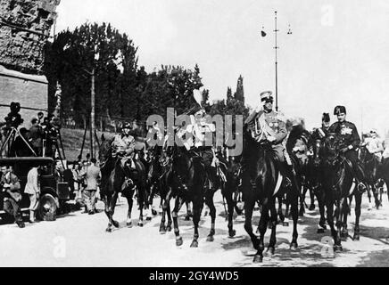 „Viktor Emanuel III., König von Italien (Mitte, Begrüßung), nahm Ende Oktober 1933, am elften Jahrestag des „Marsches gegen Rom“, zum ersten Mal an den faschistischen Feiern Teil. Hinter dem König links fährt der General und italienische Kolonialminister Emilio De Bono über die Via dei trionfi (heute Via di San Gregorio) in Rom. Auf der linken Seite haben sich Fotografen und Kamerateams eingerichtet, um das Geschehen aufzuzeichnen. [Automatisierte Übersetzung]' Stockfoto