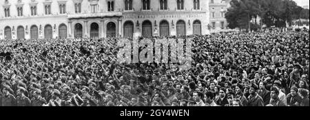 Mussolini wurde am 24. Februar 1941 im Palazzo Venezia in Rom von einer großen Menschenmenge empfangen, die sich auf der Piazza Venezia versammelt hatte. Eine Gruppe deutscher Soldaten war ebenfalls anwesend (vorne links). Zuvor war Mussolini zu Gesprächen am Teatro Adriano gewesen. Im Hintergrund befindet sich der Palazzo delle Assicurazioni Generali. [Automatisierte Übersetzung] Stockfoto