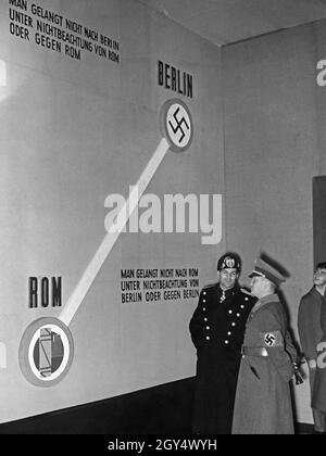 "Am 6. November 1937, dem Tag, an dem Italien dem Anti-Komintern-Pakt beigetreten ist, wurde im Reichstag in Berlin eine "Anti-Bolschewismus-Ausstellung" mit dem Titel "Bolschewismus ohne Maske" eröffnet. Das Bild zeigt einen Raum der Ausstellung, in dem die Achse Berlin-Rom visuell dargestellt wurde. Betrachtet man die Grenze zwischen den beiden Hauptstädten Rom (mit dem faschistischen Symbol Fascis) und Berlin (mit dem Nazi-Symbol Swastika), so leitet der italienische Teil der Ausstellung, General Alessandro Melchiori (links) und Gaupropaganda-Direktor von Berlin, Werner Wächter (rechts). An der Wand befinden sich zwei Versionen eines Stockfoto