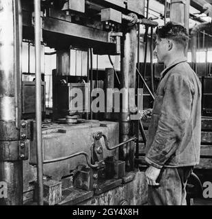 Fabrikarbeiter im Bosch-Werk: Hartgummiboxen für Starterbatterien werden auf schweren Hydraulikpressen gepresst. [Automatisierte Übersetzung] Stockfoto