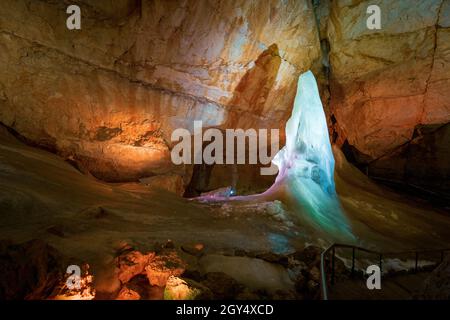 Lichtshow über Eisformationen und eine hohe Eisspitze im Parzivaldom an der Dachstein Rieseneishöhle, einer riesigen Eishöhle in den österreichischen Alpen Stockfoto