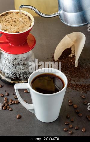 Eine Tasse Kaffee und die dritte Generation gießen über die Kaffeemaschine auf dem Steinboden Stockfoto