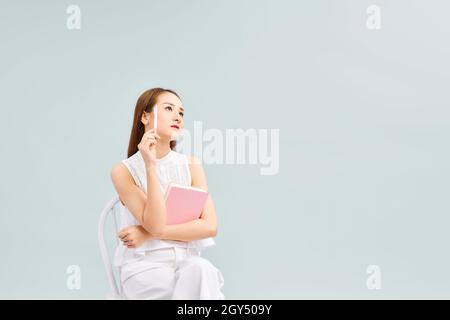 Denken Sie Über Zukünftige Pläne Nach. Nachdenklich Asiatische Mädchen Sitzen Mit Notepad Stockfoto