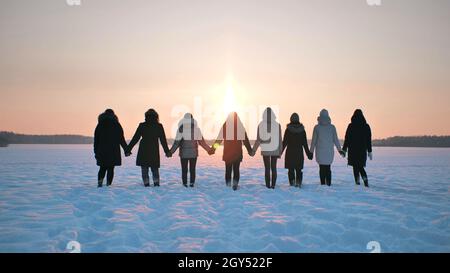 Eine Gruppe Mädchen steht im Winter mit Händen auf dem Feld. Stockfoto