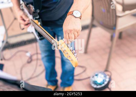 Nahaufnahme eines Musikers, der seine E-Gitarre auf der Bühne stimmt Stockfoto