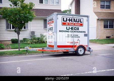 Eine U-Haul U-Box, die auf einem Anhänger vor kleinen Privathäusern in Queens, New York City, transportiert wird. Stockfoto