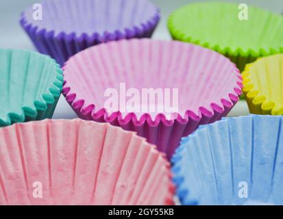 Leere, mehrfarbige Becher-Kuchenhüllen stehen auf einem Tablett bereit zum Befüllen Stockfoto