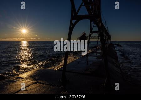 Ein silhouettierter Wellenbrecher Leuchtturm am Lake Michigan bei Sonnenaufgang. Stockfoto