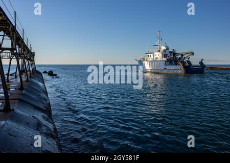 Ein Boot, das an einem Wellenbrecher vorbei auf den Lake Michigan fährt Stockfoto