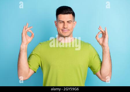 Foto Porträt Mann in grünen T-Shirt ruhig meditieren friedlich isoliert pastellblau Hintergrund Stockfoto