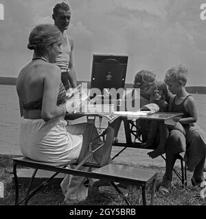 Eine kleine Campinggesellschaft hört Musik über das electrola Koffer 106 Grammophon, Deutschland 1930er Jahre. Ein Campingplatz Gruppe die Musik von einem electrola Koffer 106 Koffer Grammophon gespielt, Deutschland 1930. Stockfoto