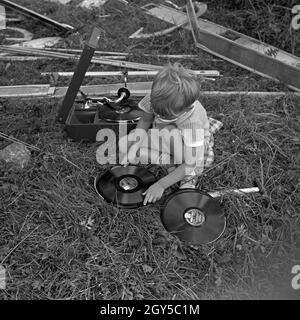 Ein kleiner Junge sortiert Schellackplatten bei Einems Electrola Koffer 106 Grammophon, Deutschland 1930er J Jahre. Ein kleiner Junge Auswahl einiger shellack Datensätze in der Nähe einer Electrola Koffer 106 Koffer Grammophon, Deutschland 1930. Stockfoto