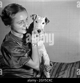 Eine Dame mit Hund im Fotostudio in zeitgenössischer Mode, Deutschland 1930er Jahre. Eine Frau und ihr Hund Haustier auf dem Foto Studio in der zeitgenössischen Mode, Deutschland 1930. Stockfoto