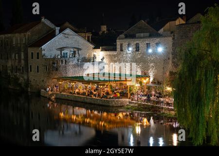 Nachtaufnahme eines beleuchteten Restaurants an einem Flussufer in Trebinje Stockfoto