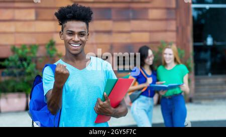 Jubelnde afroamerikanische männliche Studentin mit einer Gruppe internationaler Studenten im Freien in der Stadt Stockfoto